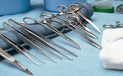 Surgical instruments lined up on table including scissors, forceps and tweezers