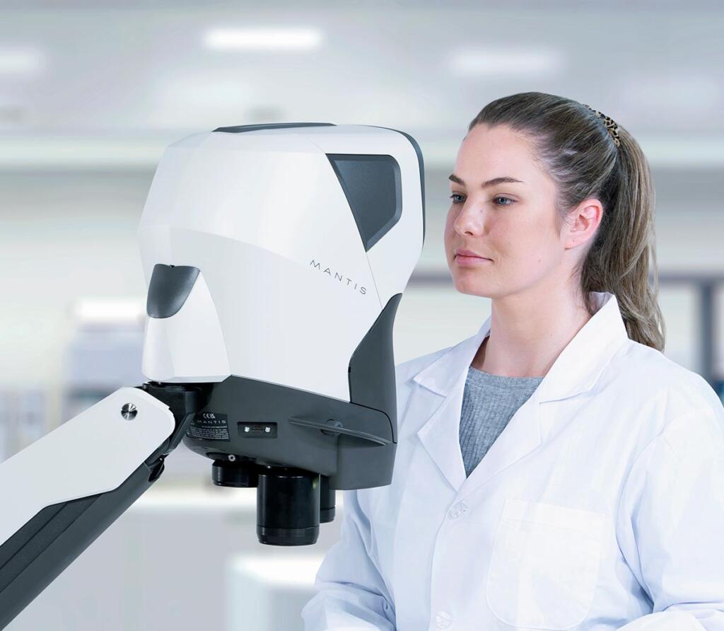 Dental technician in white coat looking into Mantis viewer